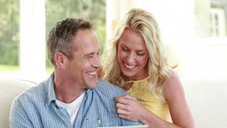 happy couple using tablet on sofa
