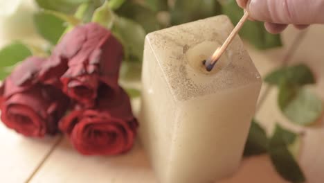 lighting a candle with bouquet of red roses background