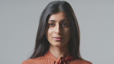 Head-And-Shoulders-Studio-Portrait-Of-Serious-Young-Businesswoman-Against-Plain-Background