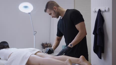 esthetician performing a professional beauty treatment on a client's legs