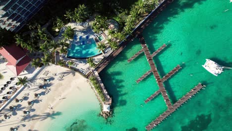 Overhead-shot-of-Caribbean-coastline-with-turquoise-water,-yachts,-docks,-palms-and-resort-hotels