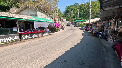 a car drives down a bustling market road.