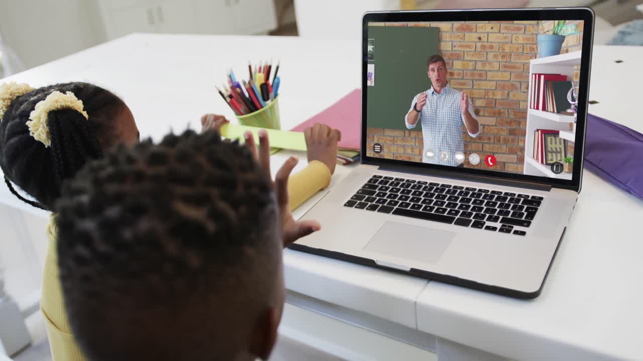 Irmãos diversos e felizes em aula por videochamada no laptop, com professor, em câmera lenta.