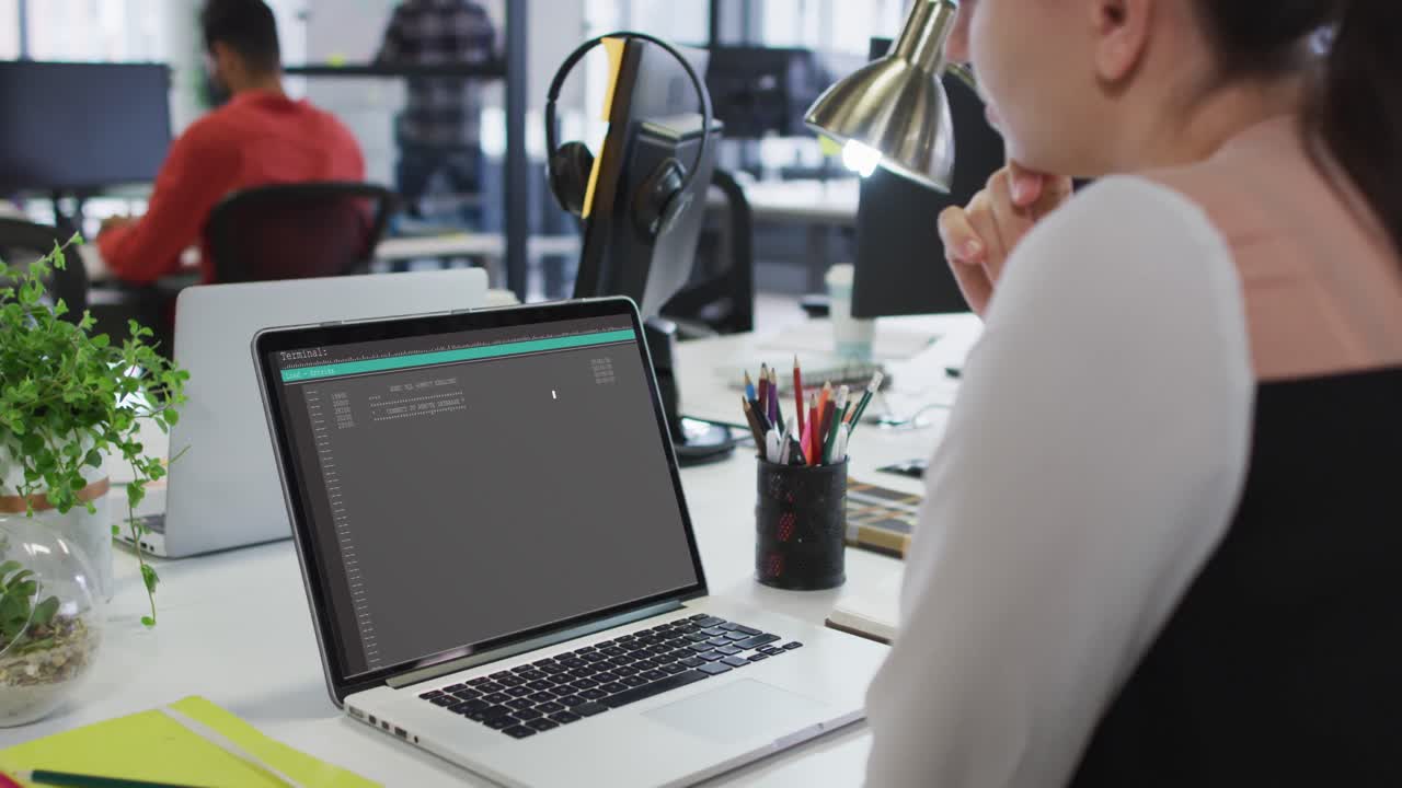 Caucasian woman sitting at desk watching coding data processing on laptop screen