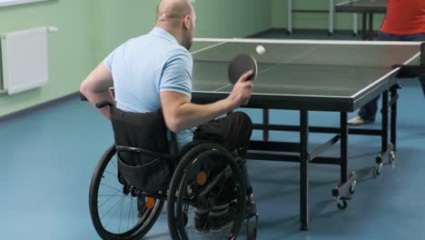 a man in a wheelchair plays ping pong. people with disabilities play table tennis. rehabilitation of the disabled. paralympic sport.