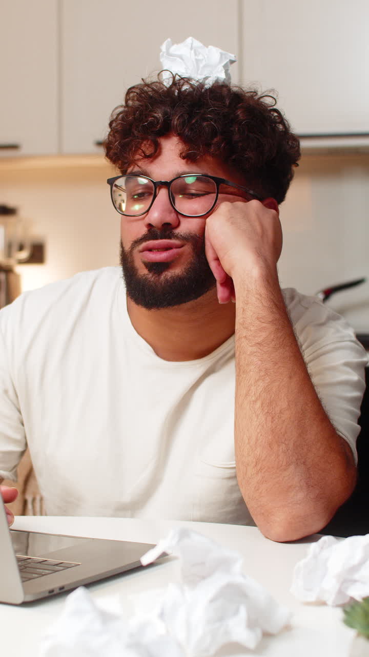 Arabian man fights creative block writes ideas for project crumpled papers desk frustrated evening