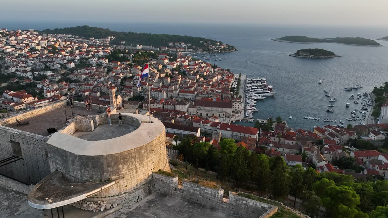 Parallax drone shot of Hvar City Fortress in the day with sunshine and Adriatic Sea in Croatia