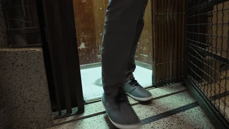 medium shot of a person in the old vintage elevator rising and arriving at the floor of a building, getting out and shutting the steel door