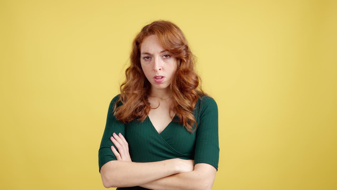 Unhappy redhead woman with arms crossed on yellow background