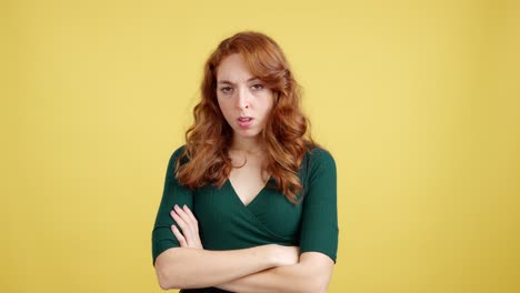 unhappy redhead woman with arms crossed on yellow background