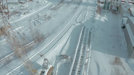 snowy industrial facility with crane and conveyor