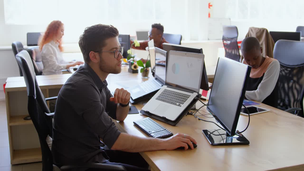 Side view of young cool mixed-race business team working at desk in a modern office 4k
