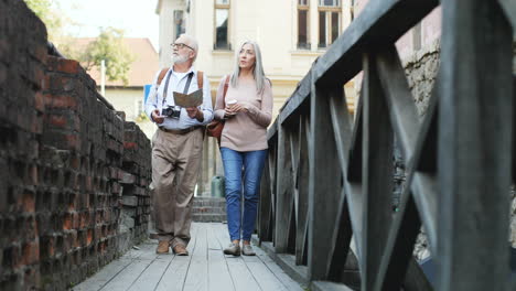 View-From-Below-Of-Senior-Couple-With-A-Map-And-Coffee-Walking-A-Narrow-Bridge