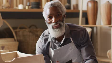 portrait of african american male carpenter with clipboard smiling sitting in a carpentry shop