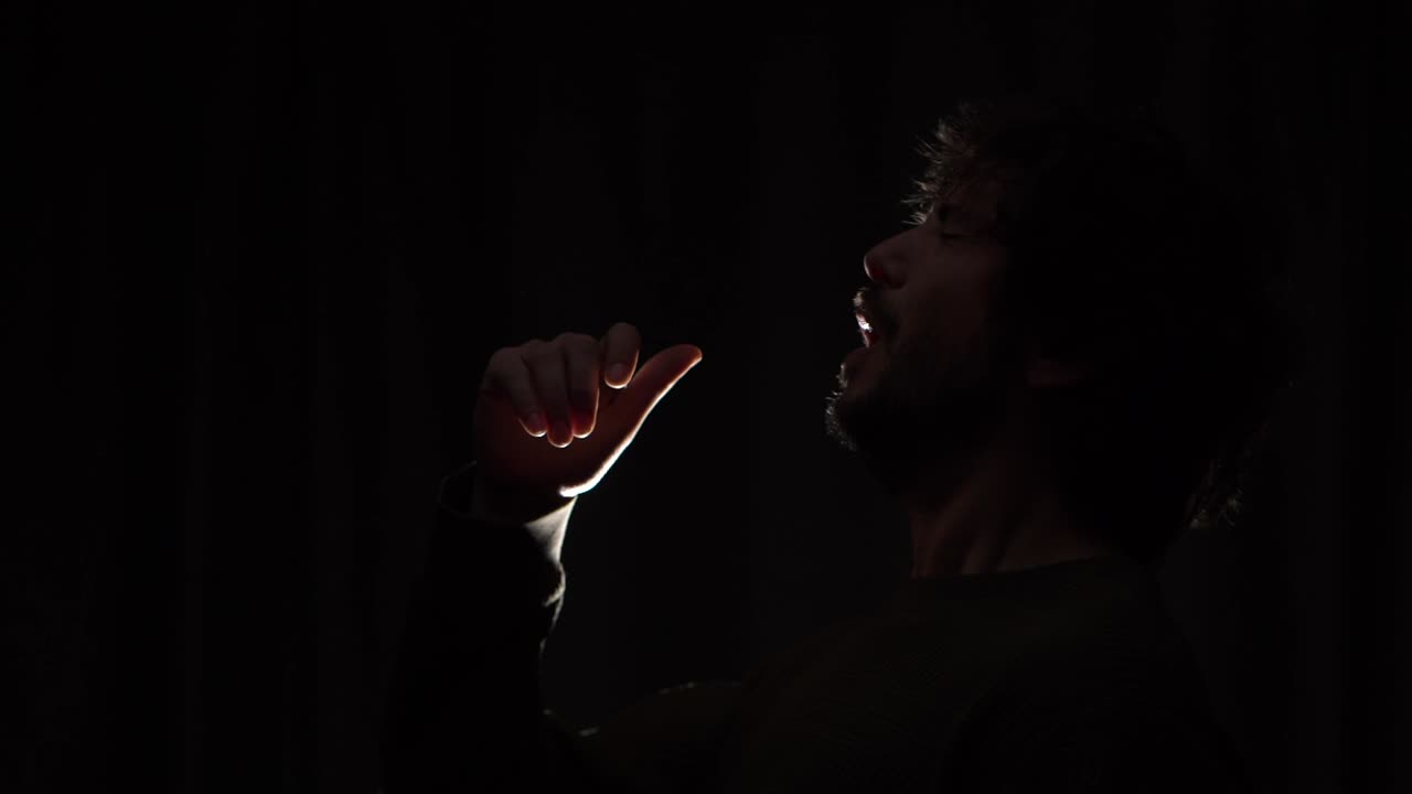 A sick man sneezing uncomfortably with a dark background