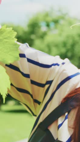 a captivating moment of joy: a woman with long hair in a straw hat and striped shirt enjoying nature while smiling and engaged in an afternoon activity
