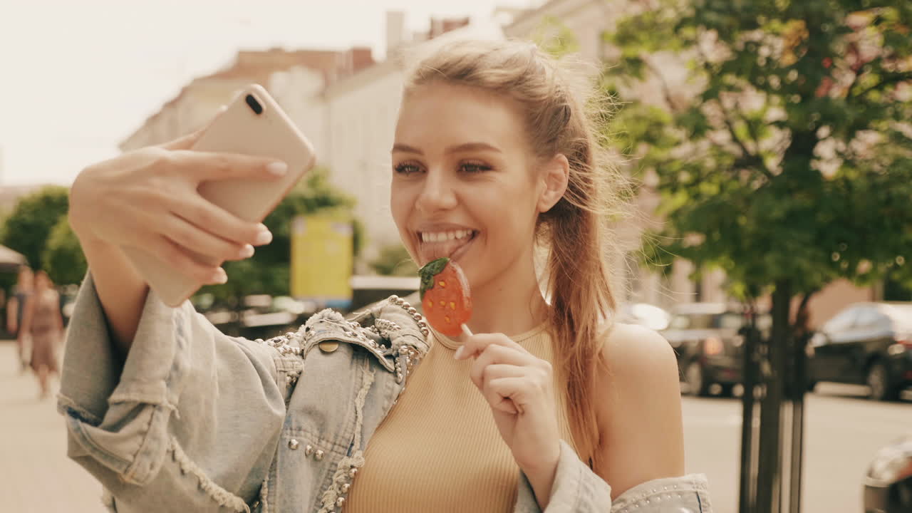 mujer tomando una selfie con piruleta en la calle de la ciudad