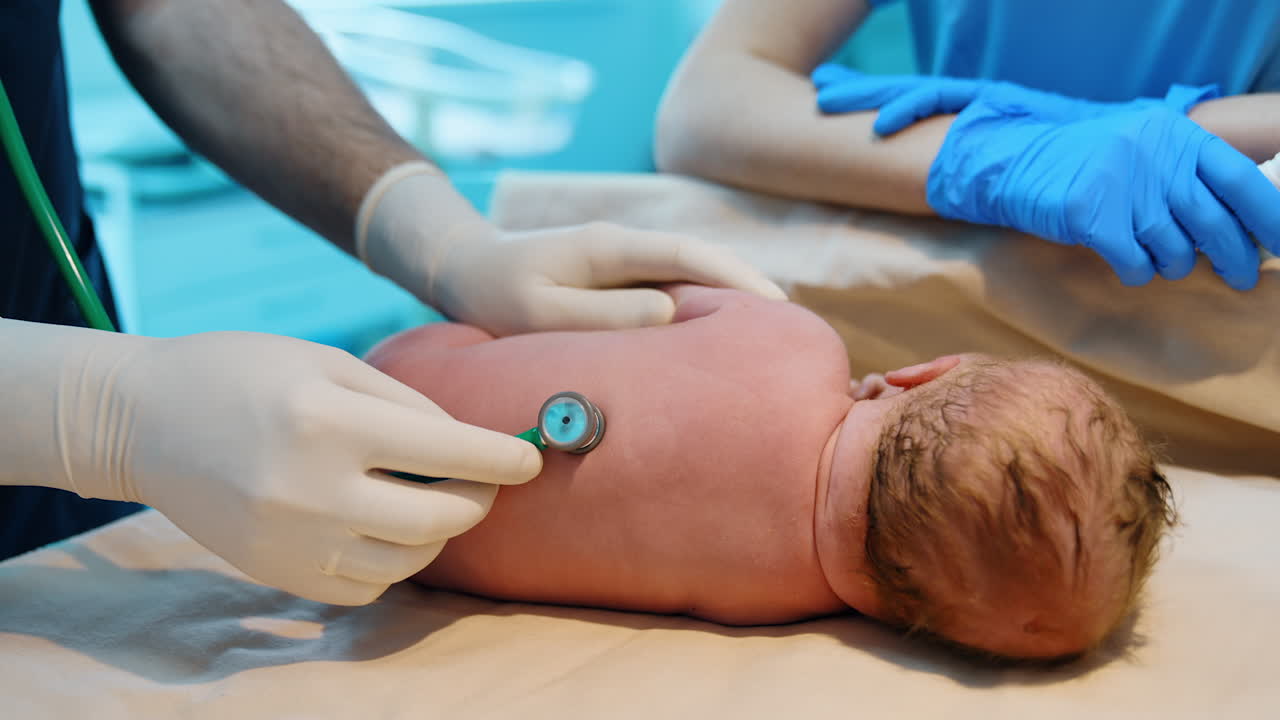 Caucasian newborn is put on its side. Pediatrician listens to baby's heart and lungs after birth. Close up.