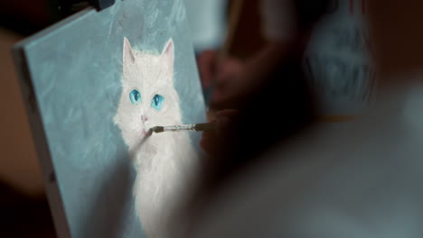 unrecognizable girl artist drawing picture of white cat on canvas in studio.