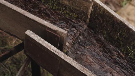 Close-up of a wooden gutter with water flowing inside