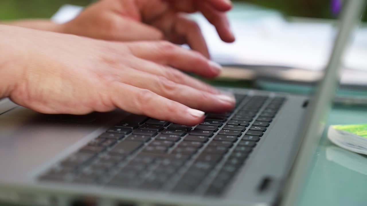 Hands typing on a laptop keyboard indoors