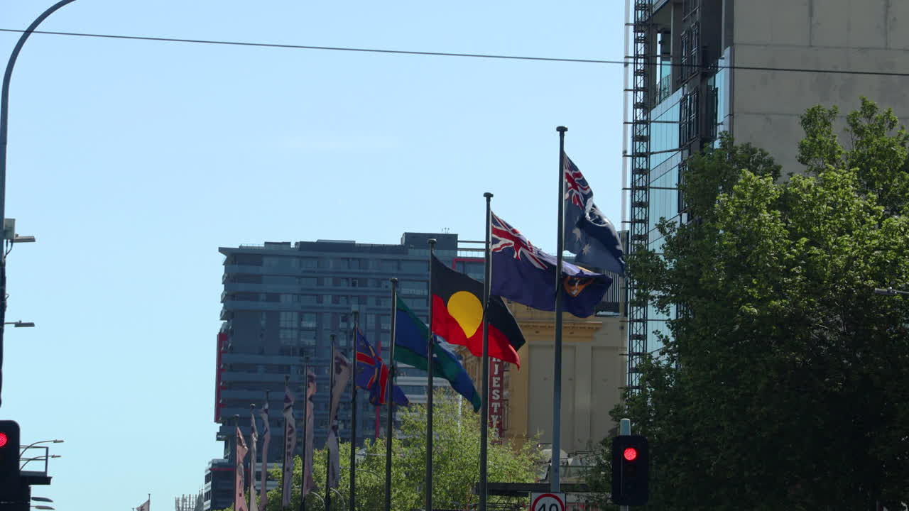 Flags of Australia, Aboriginal Australia, and Torres Strait Islander people blowing in the wind in Adelaide, Australia. Perfect for projects related to travel, diversity, and Australian culture.