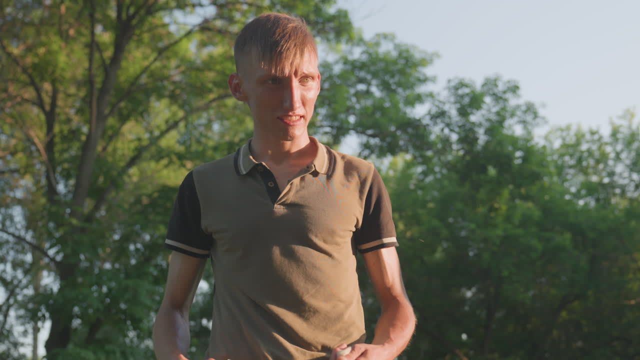 Caucasian Man In Park Fidgeting With Small Object, Scanning Surroundings Under Warm Sunset, Tense Posture With Guarded Gaze, Nervous Breath, Isolated Mood With Subtle Paranoia And Compulsive Movement