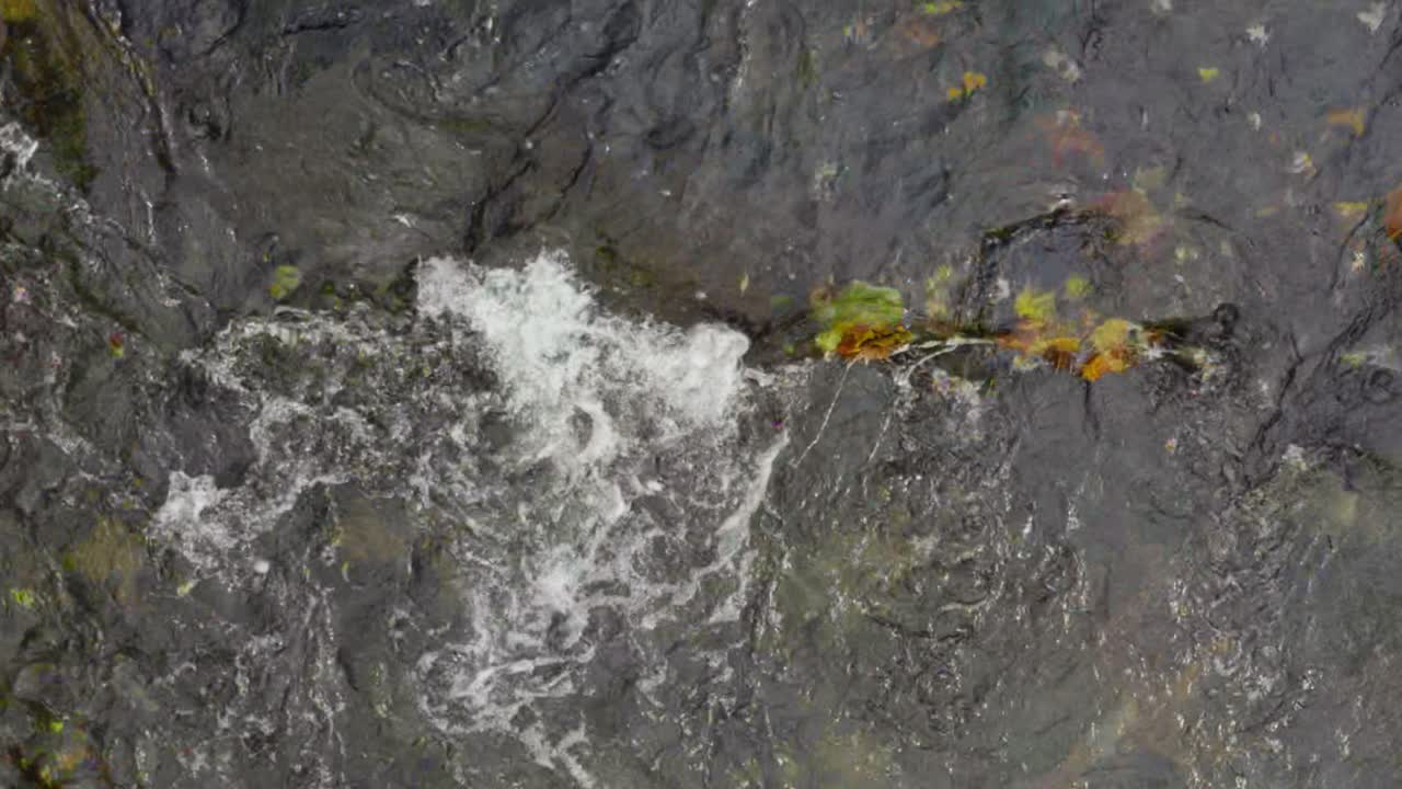 A slow motion overhead clip of water flowing in a river
