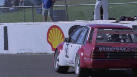 a racing car drives around a track as people watch