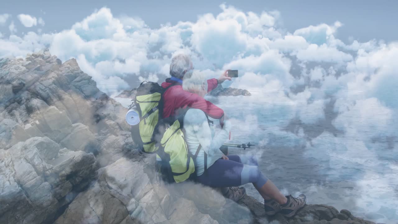 couple sitting cliff over ocean, woman tapping phone showing tech selfie overlay capturing moment