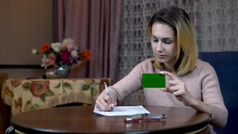 girl with a credit card and documents. fills the card data on a piece of paper. green screen