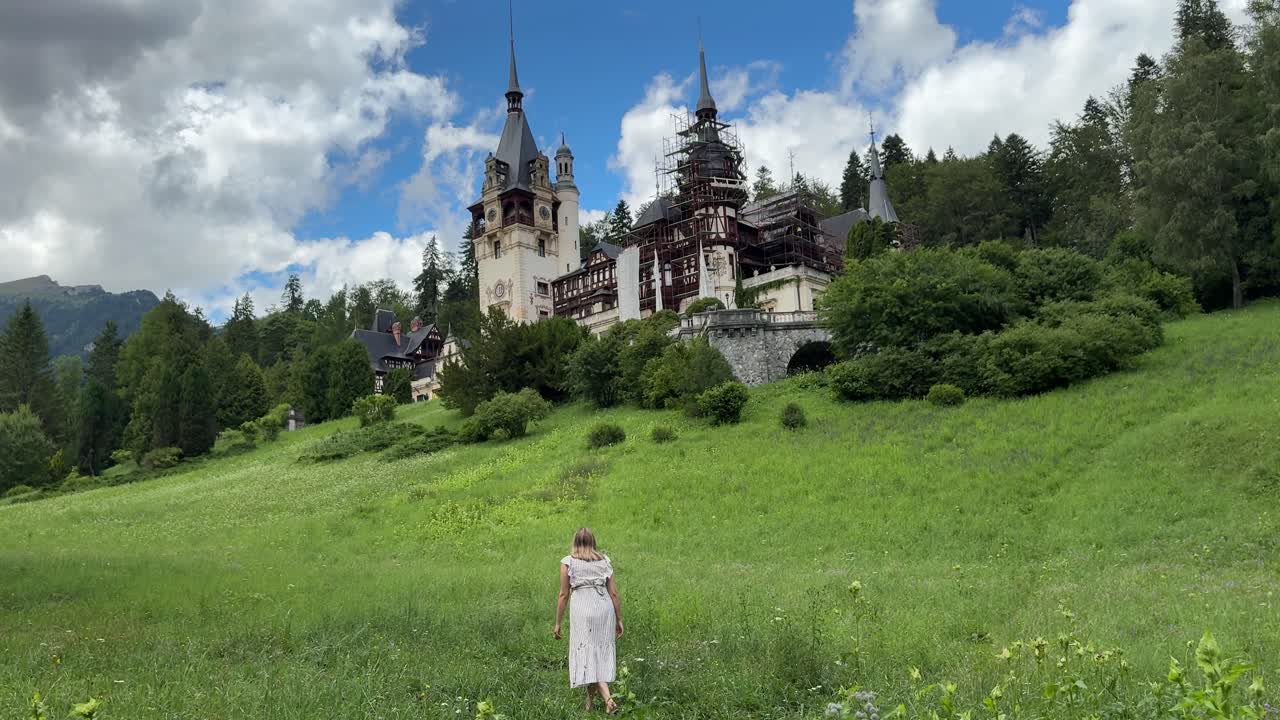 Woman in dress walking towards Peles Castle in Transylvania