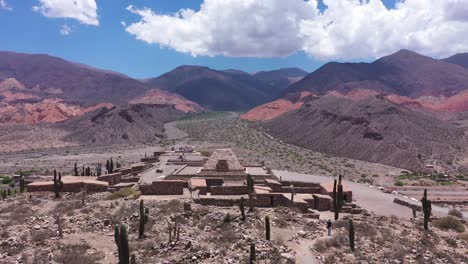 Aerial-view-of-a-small-village-with-an-Inca-temple-in-the-middle-of-a-mountainous-and-desert-valley-in-Jujuy,-Pucará-Argentina