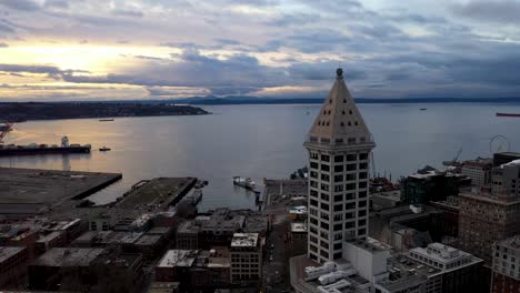 aerial of seattle's smith tower overlooking the sun setting over the puget sound