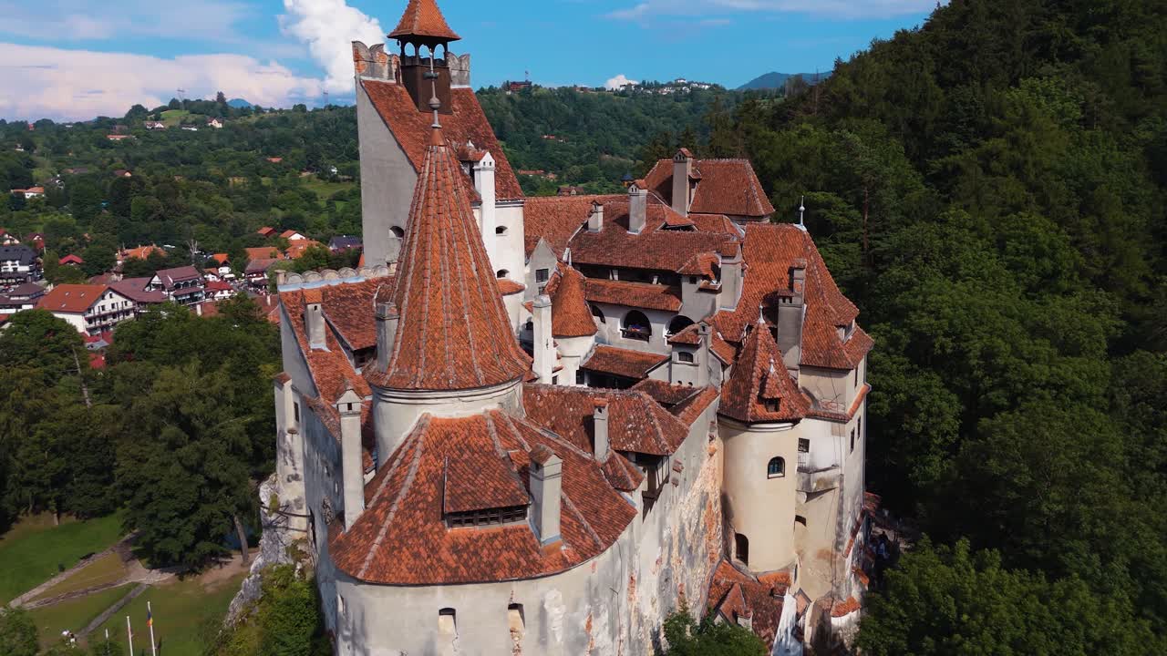 Drone orbita intorno ai tetti del Castello di Bran sopra colline boscose