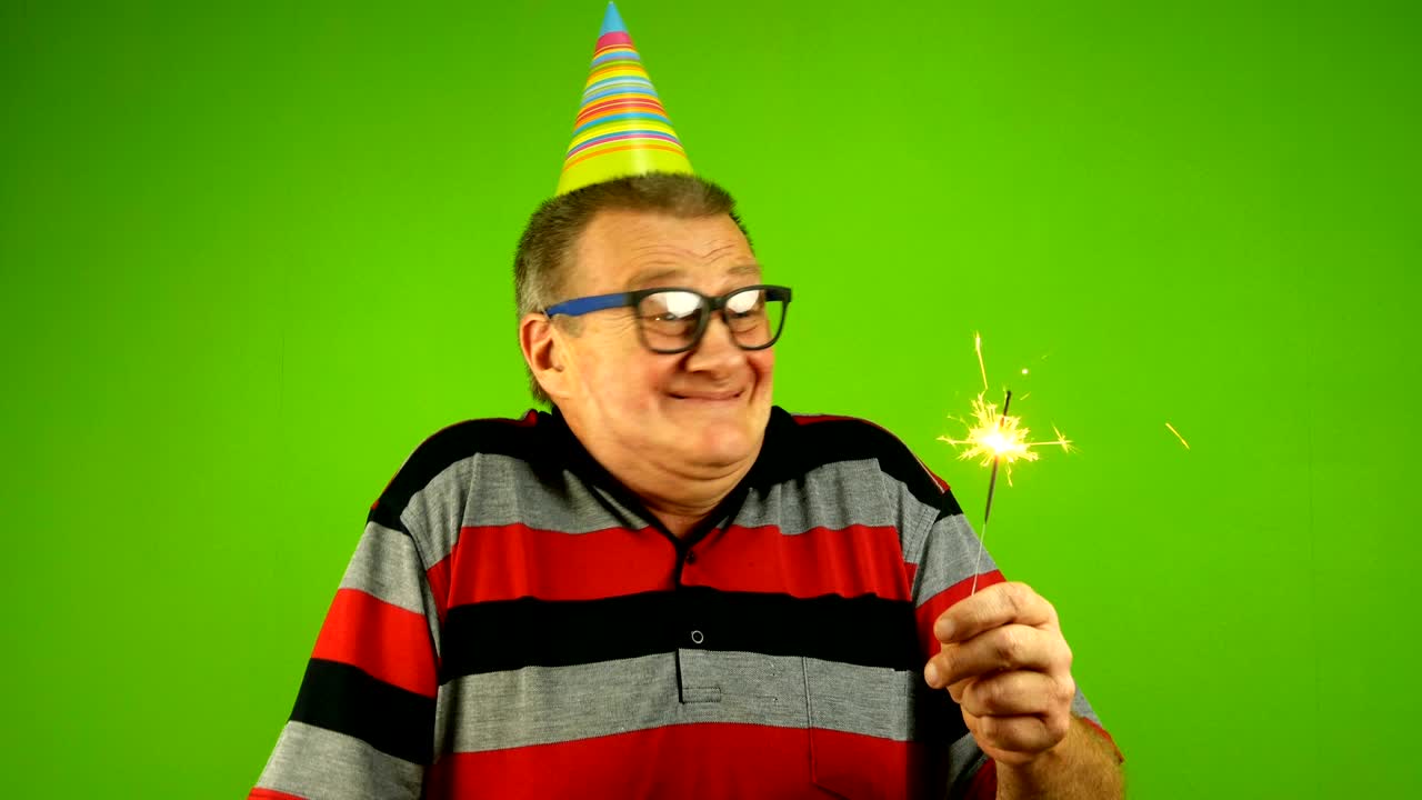 Uomo anziano di etnia caucasica, in abiti casual e cappellino di compleanno.