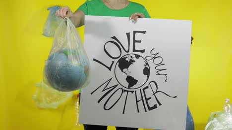 unrecognizable woman with protesting poster and earth globe in plastic package. ecology pollution