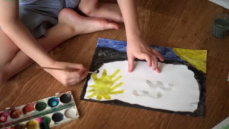 a child on the floor draws a drawing with watercolors 02