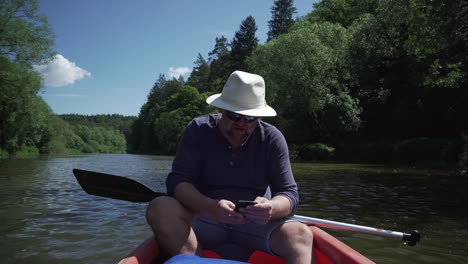 Man-using-cellphone-in-canoe-on-river,-calling-for-help,-no-reception,-front-view