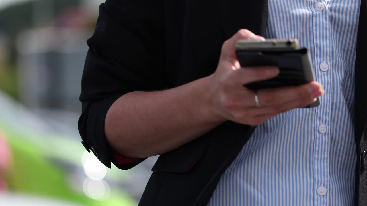 A woman in business attire is looking for her car in a crowded parking lot using a mobile application