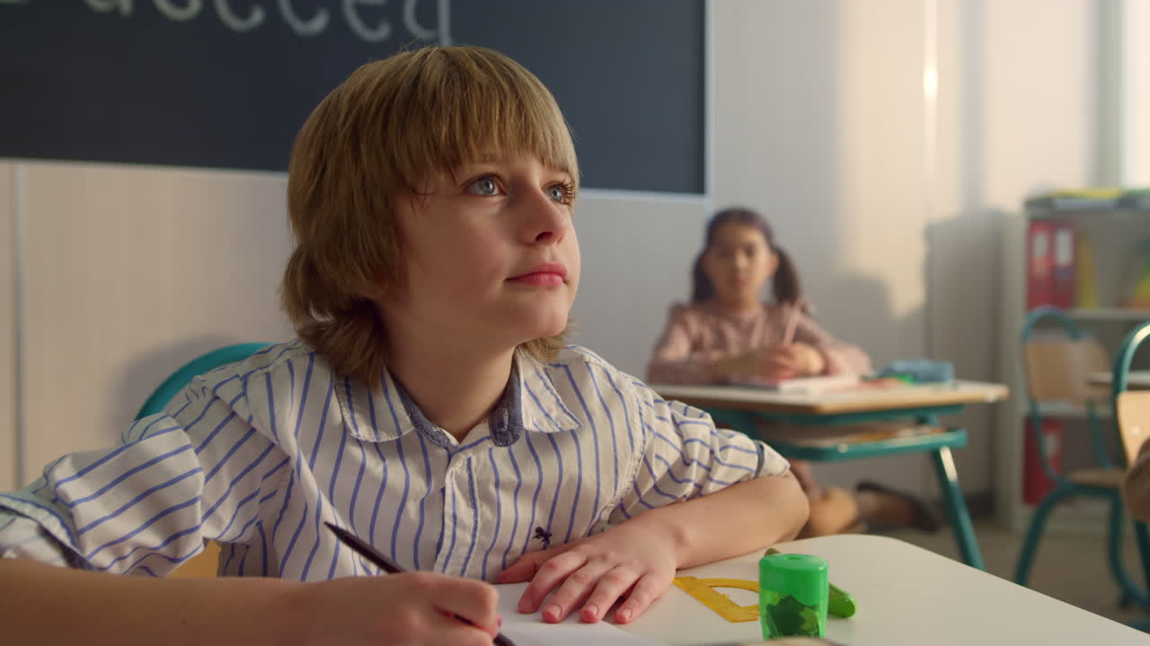 Bambino concentrato che studia in classe. Bambino intelligente che scrive sul quaderno durante la lezione.