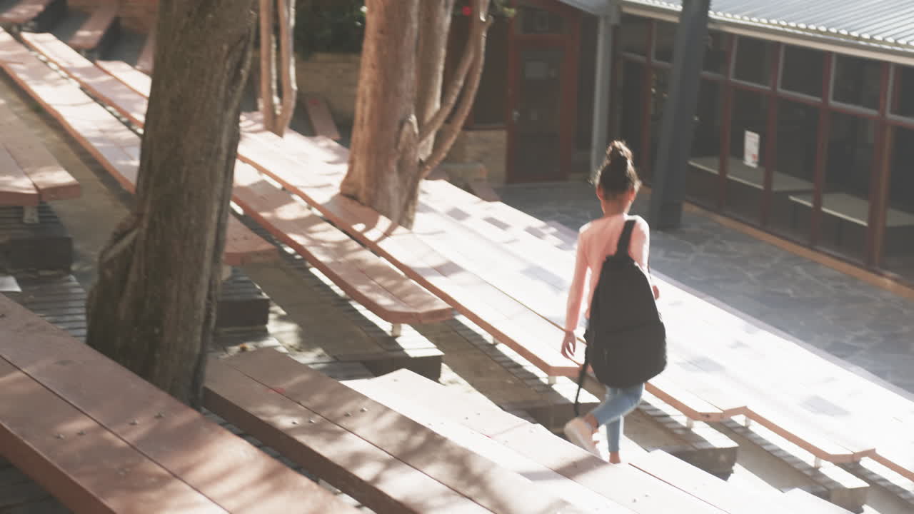 Walking down outdoor steps, student carrying bag in school courtyard