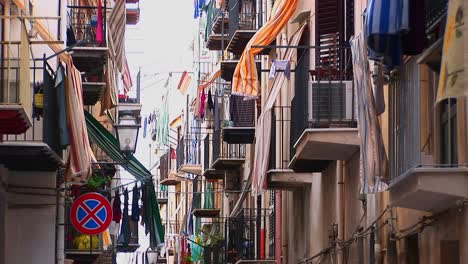 An-alley-between-closely-placed-houses-with-clothes-drying-from-balconies-and-staircases-in-Cefalu-Italy--