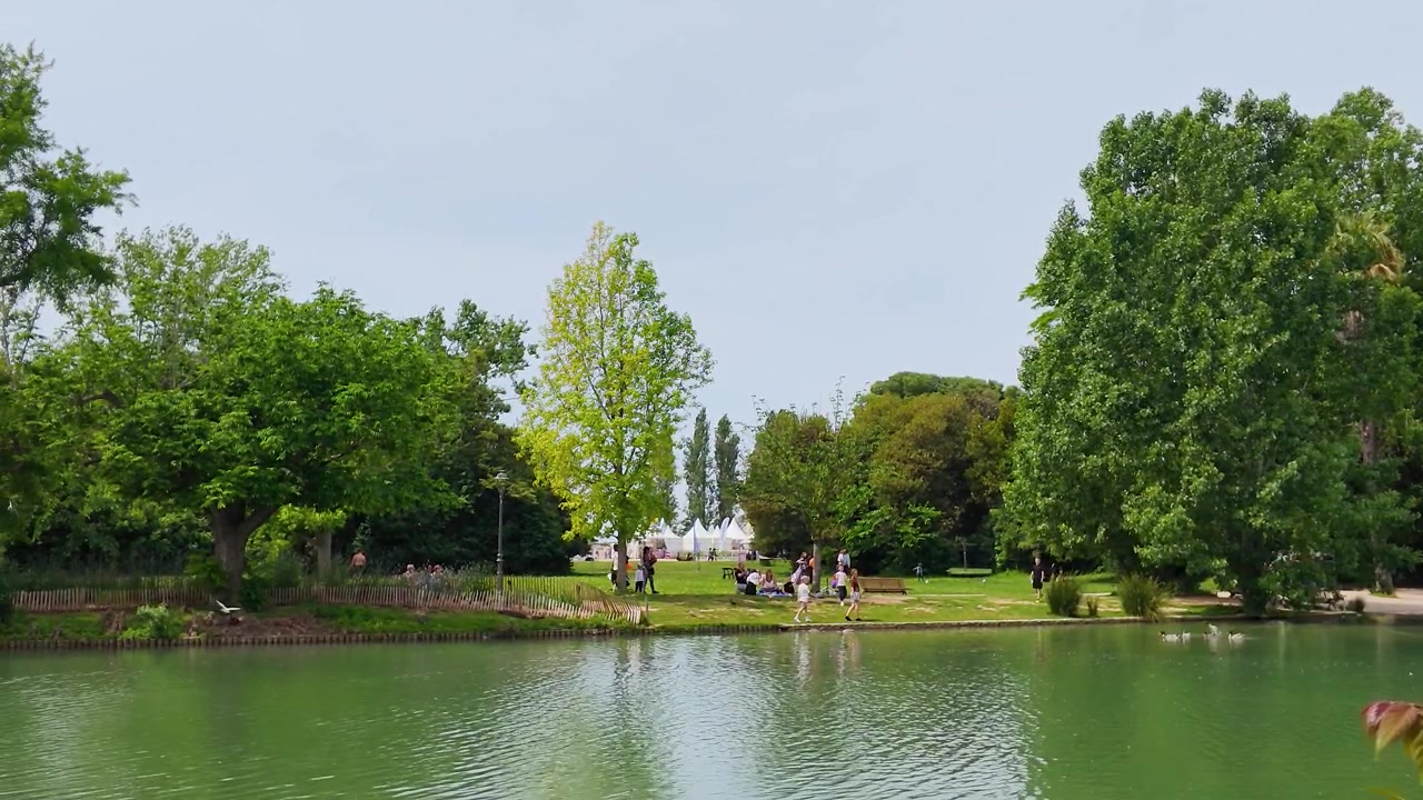 Parc verdoyant avec un lac et des gens profitant d'une journée ensoleillée