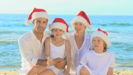 happy family wearing christmas hats on a beach