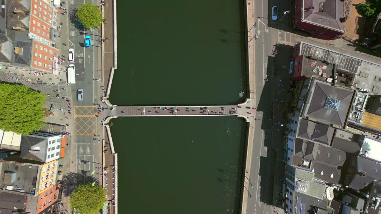 Ultra-wide, descending ascending aerial of the Ha'penny Bridge and the River Liffey in Dublin City Centre, Ireland on a bright and sunny day. Filmed in 4K, 60FPS and with Rec709 color.