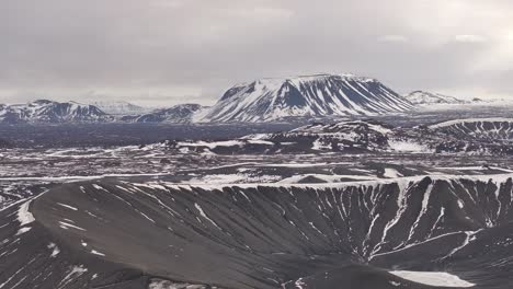 drone view of hverfjall crater near mývatn, iceland, snowy volcanic landscape with ridges and mountains.