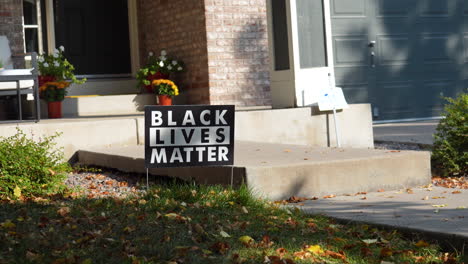 black lives matter yard sign on front porch of house steps with flowers