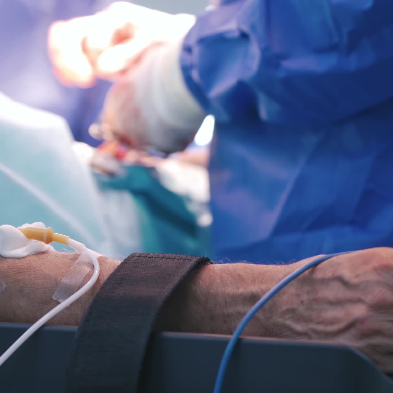Surgery operation. Human hand with bandage and medical pipes on the background of operating process in hospital. Surgical treatment concept.