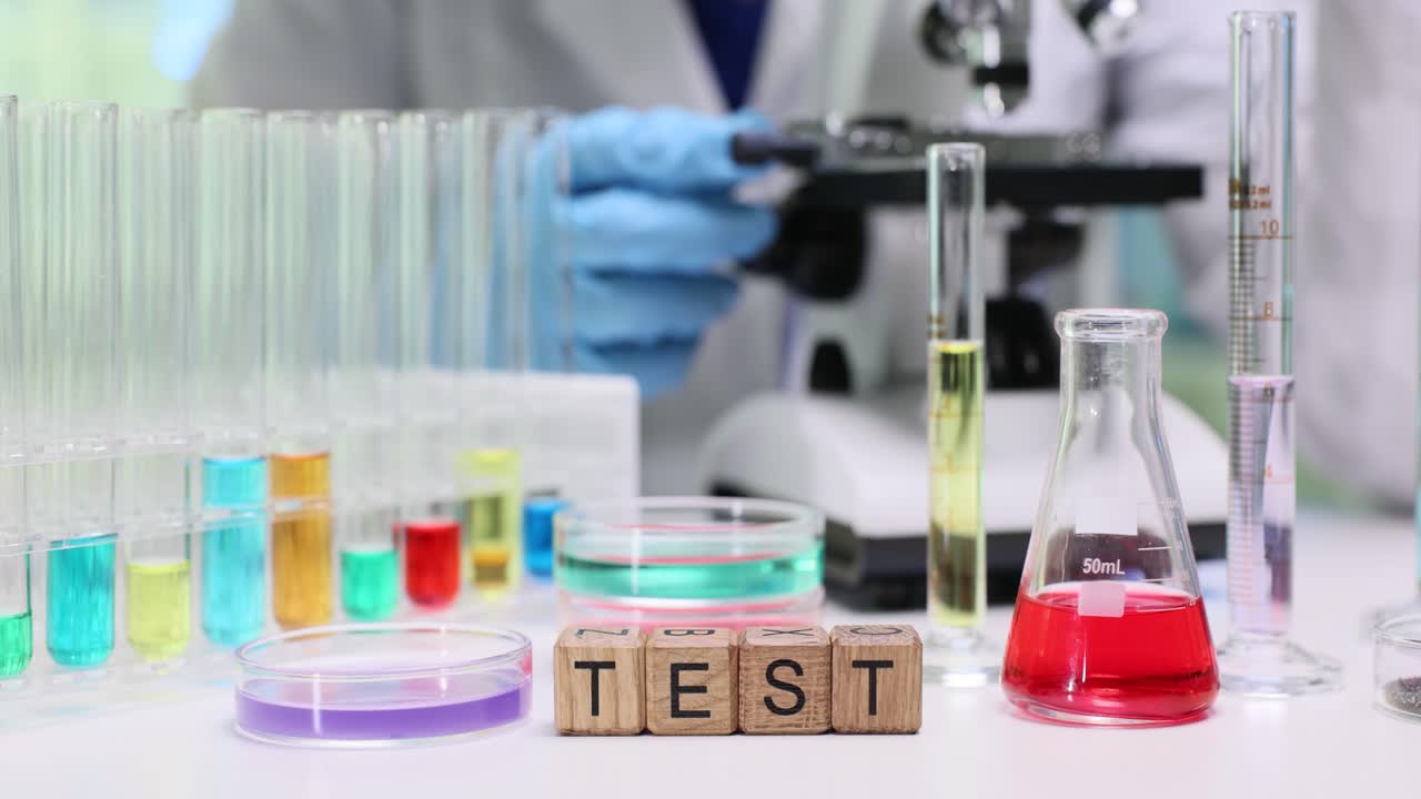 Allestimento di laboratorio con provette e scienziato che utilizza il microscopio.